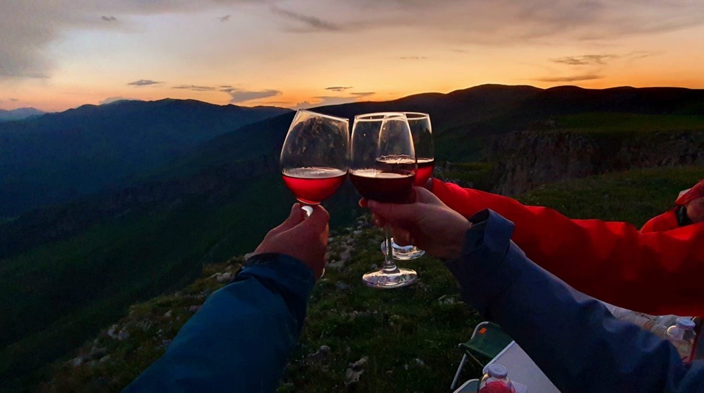 Glasses of wine raised against a mountain sunset